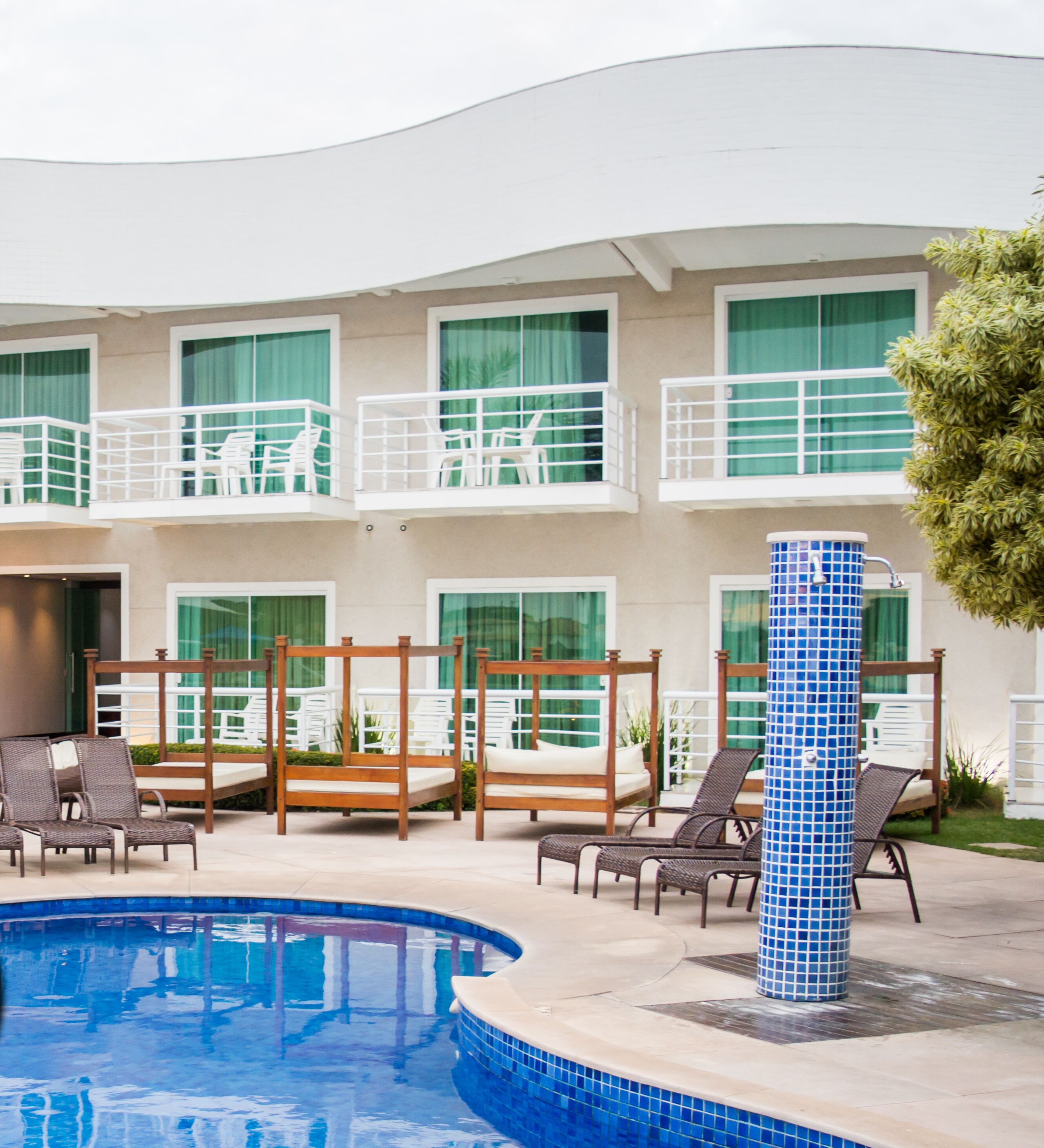 A pool area with lounge chairs and a tiled column.