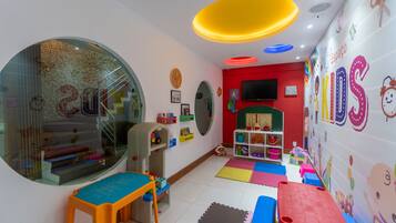 Une salle de jeux pour enfants avec des tapis de jeu colorés, des jouets et des décorations murales à vocation éducative.