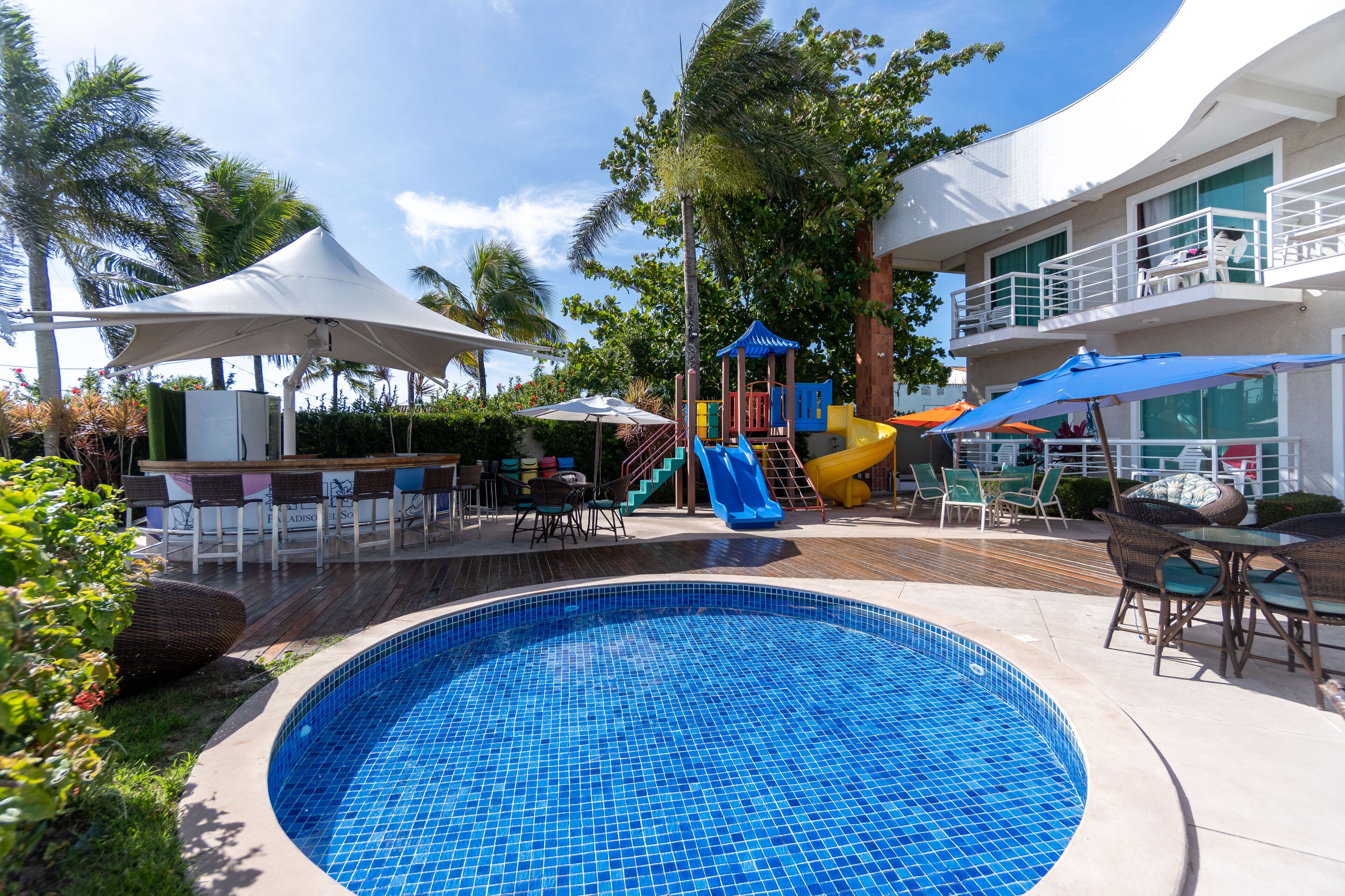 A swimming pool with a slide, outdoor seating, and a play area.