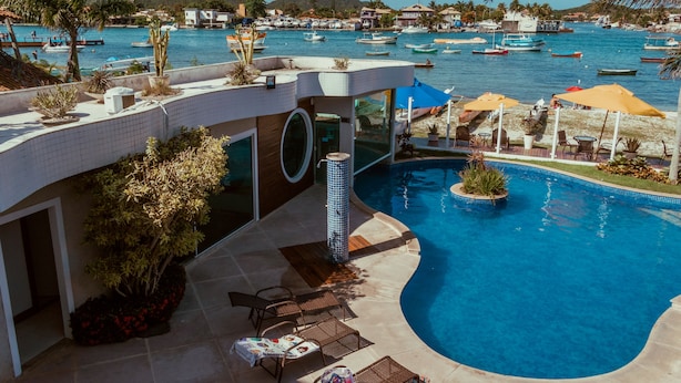 Un área de piscina moderna con vistas al puerto deportivo, sillas de descanso y un diseño de piscina circular.
