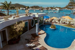 Un área de piscina moderna con vistas al puerto deportivo, sillas de descanso y un diseño de piscina circular.