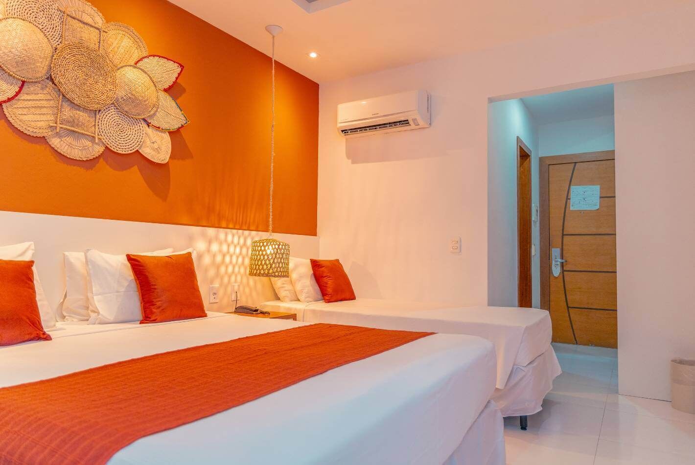 Une chambre d’hôtel avec deux lits, un grand élément décoratif mural, un appareil de climatisation et une porte en bois.