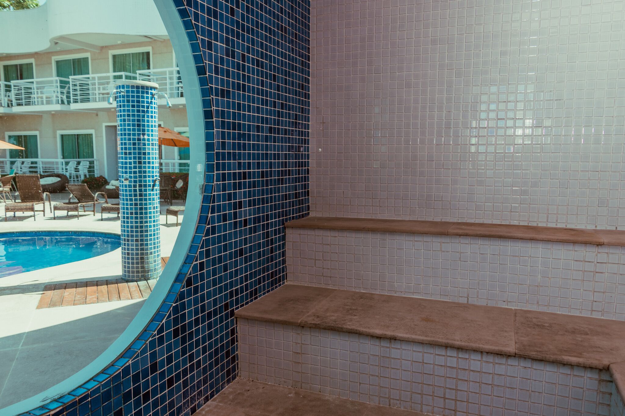 A pool area with a blue-tiled wall and steps leading to a balcony.