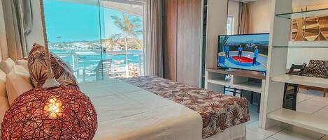 Une chambre d’hôtel moderne dotée d’un grand lit, d’une télévision et offrant une vue sur la mer.