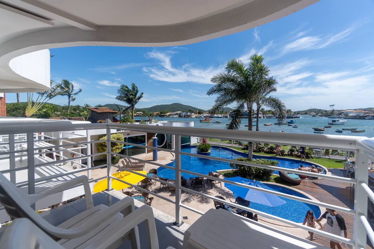 Un área de piscina con varias piscinas, sillas de descanso y sombrillas.