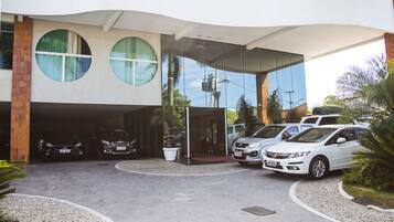 A modern building with a covered parking area, featuring a curved roof and large circular windows.