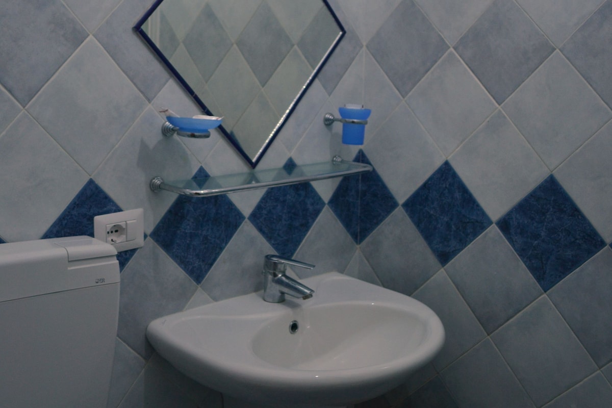 Ein Badezimmer mit Waschbecken, Spiegel und blauen Fliesen.