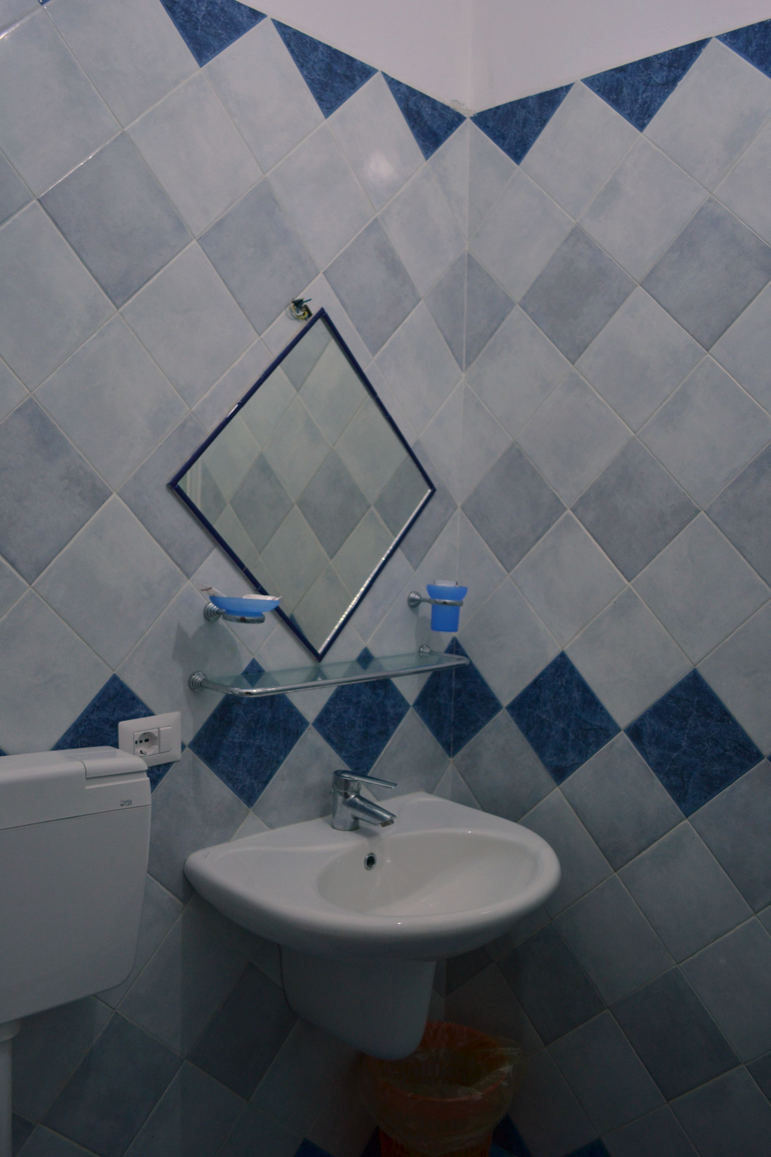 A bathroom with a white sink, a mirror, and blue and white tiles.