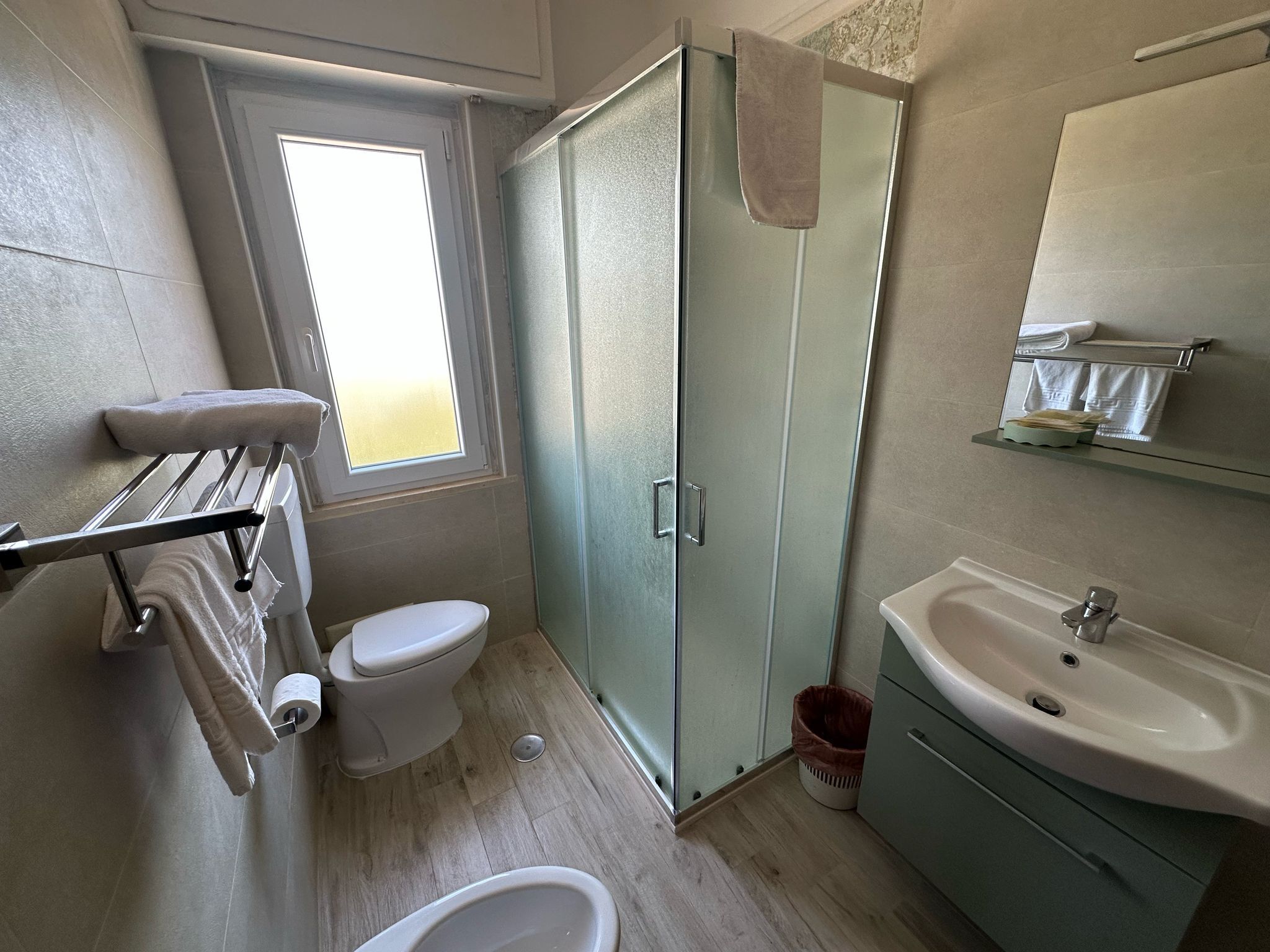 Ein Badezimmer mit Toilette, Duschkabine aus Glas, Waschbecken und Handtuchhalter.