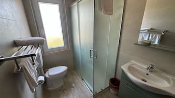 Ein Badezimmer mit Toilette, Duschkabine aus Glas, Waschbecken und Handtuchhalter.