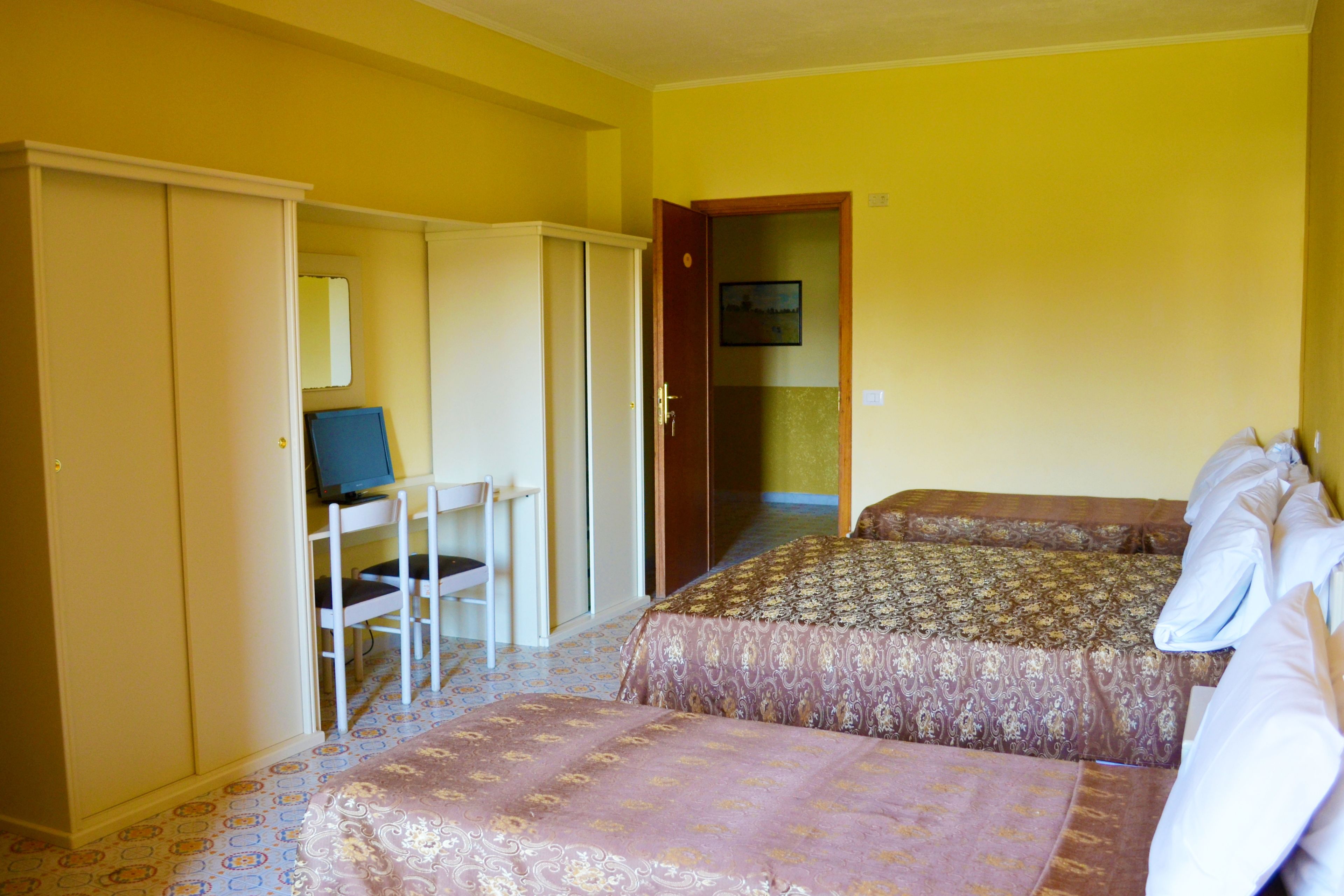 A room with two beds, a desk, and a chair.