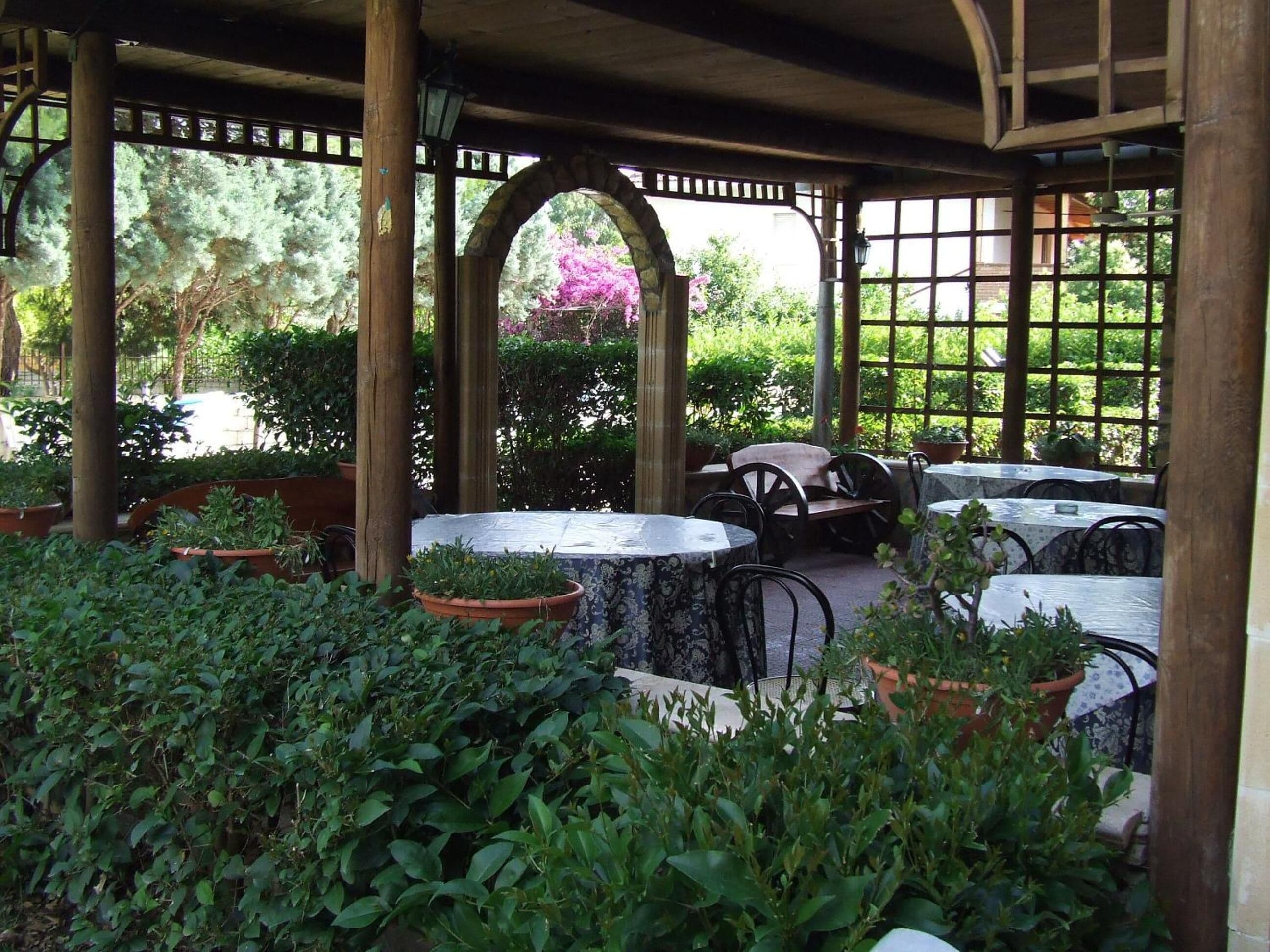 An outdoor patio area with wooden columns, tables, and chairs.