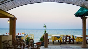 Un área de comedor al aire libre con mesas y sillas, con vista al mar.