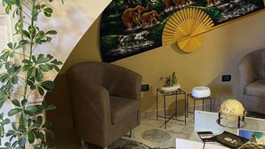 Una sala de estar con un sofá, una mesa de centro, una planta y un cuadro colgado en la pared de elefantes.