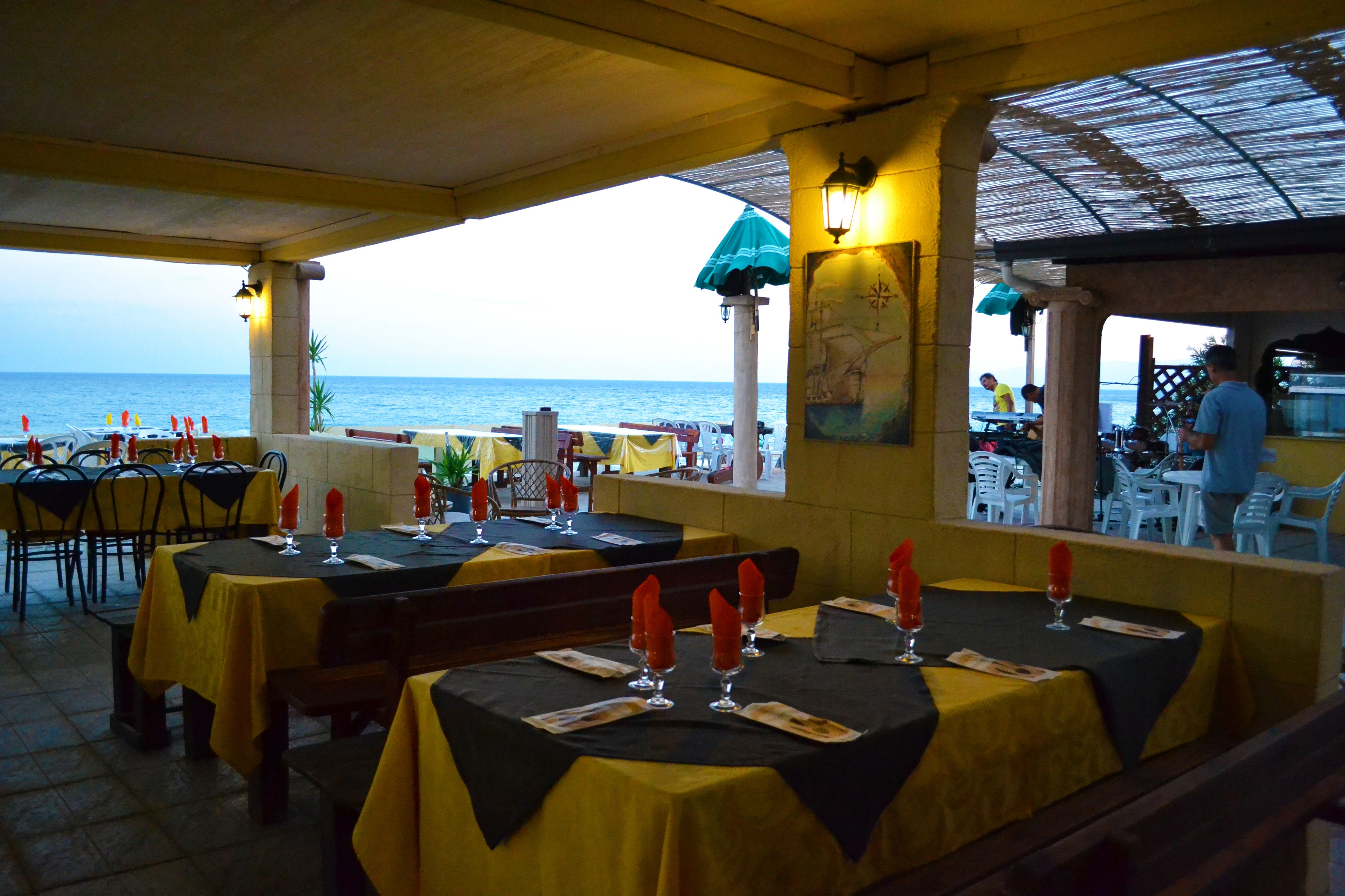 Un área de comedor al aire libre con mesas preparadas para dos, con vista al mar.