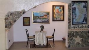 Una habitación con un arco de piedra, una mesa con sillas y obras de arte enmarcadas en las paredes.