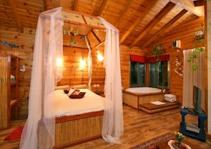 Una habitación de cabaña de madera con una cama con dosel, un jacuzzi y un televisor.