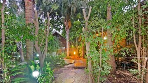 A garden with a wooden structure, stone pathway, and various plants. - Siesta (Ramot)