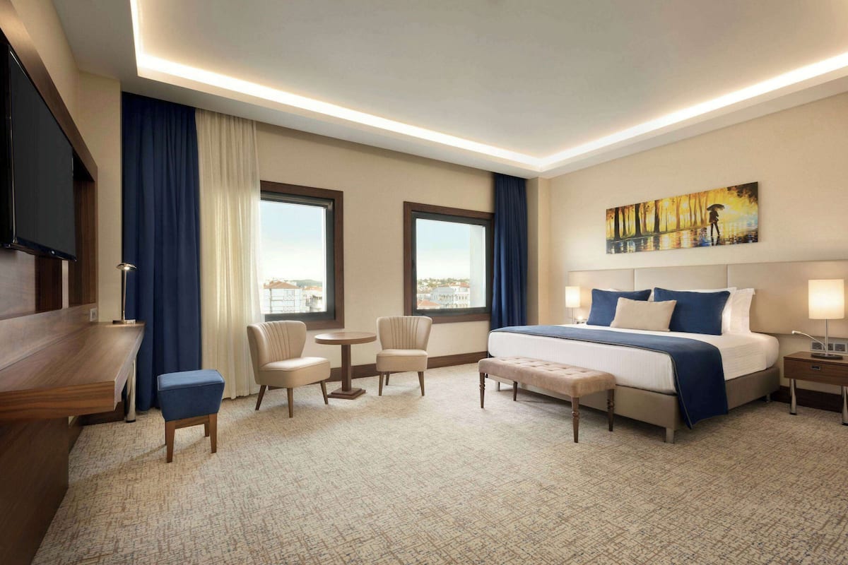 Un hotel amb llit, escriptori, dues cadires, taula petita i un quadre a la paret.
