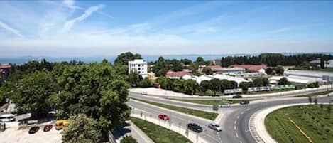 A multi-lane highway with vehicles, surrounded by greenery and buildings.