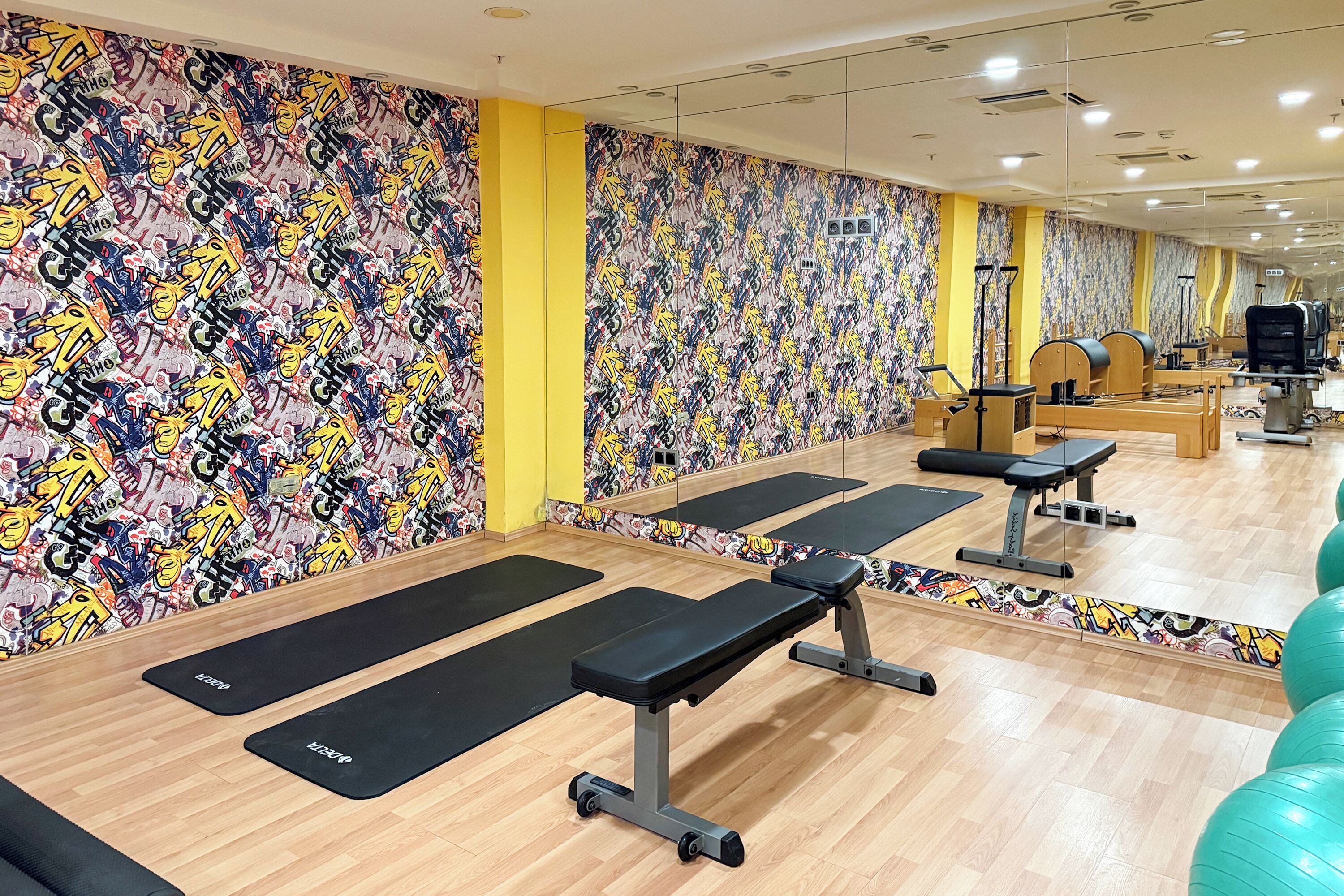 A gym with mirrored walls, wooden flooring, and exercise equipment.