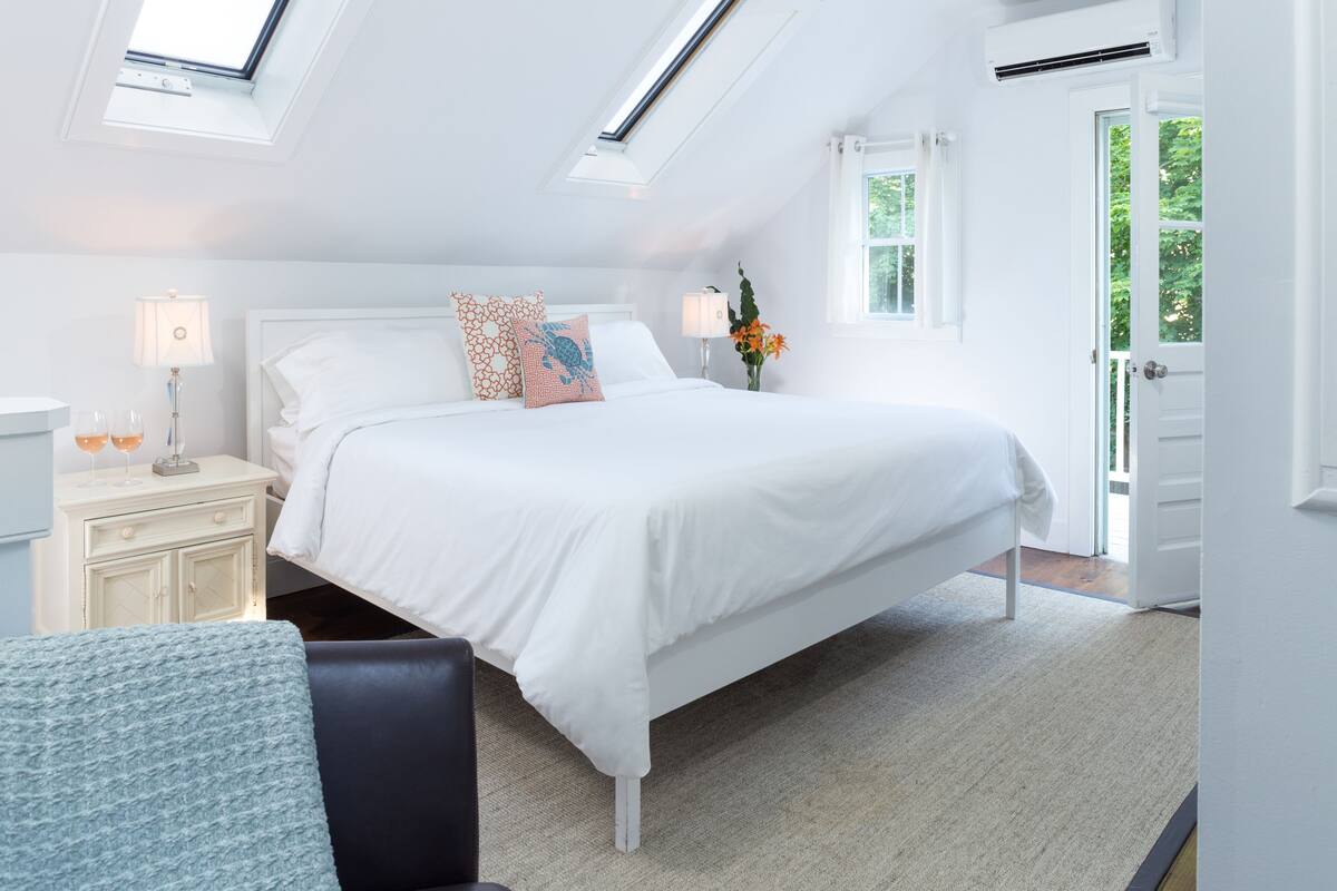 A bedroom with a bed, bedside tables, a lamp, a window, and a door.