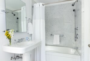 Une salle de bain avec un lavabo blanc, un miroir et un espace douche.