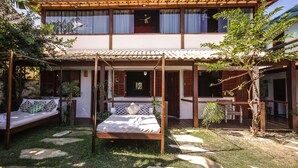 A two-story building with a covered patio area, a bed with a canopy, and a dining area. - Pousada NOVA ESTRELA INN (Búzios)