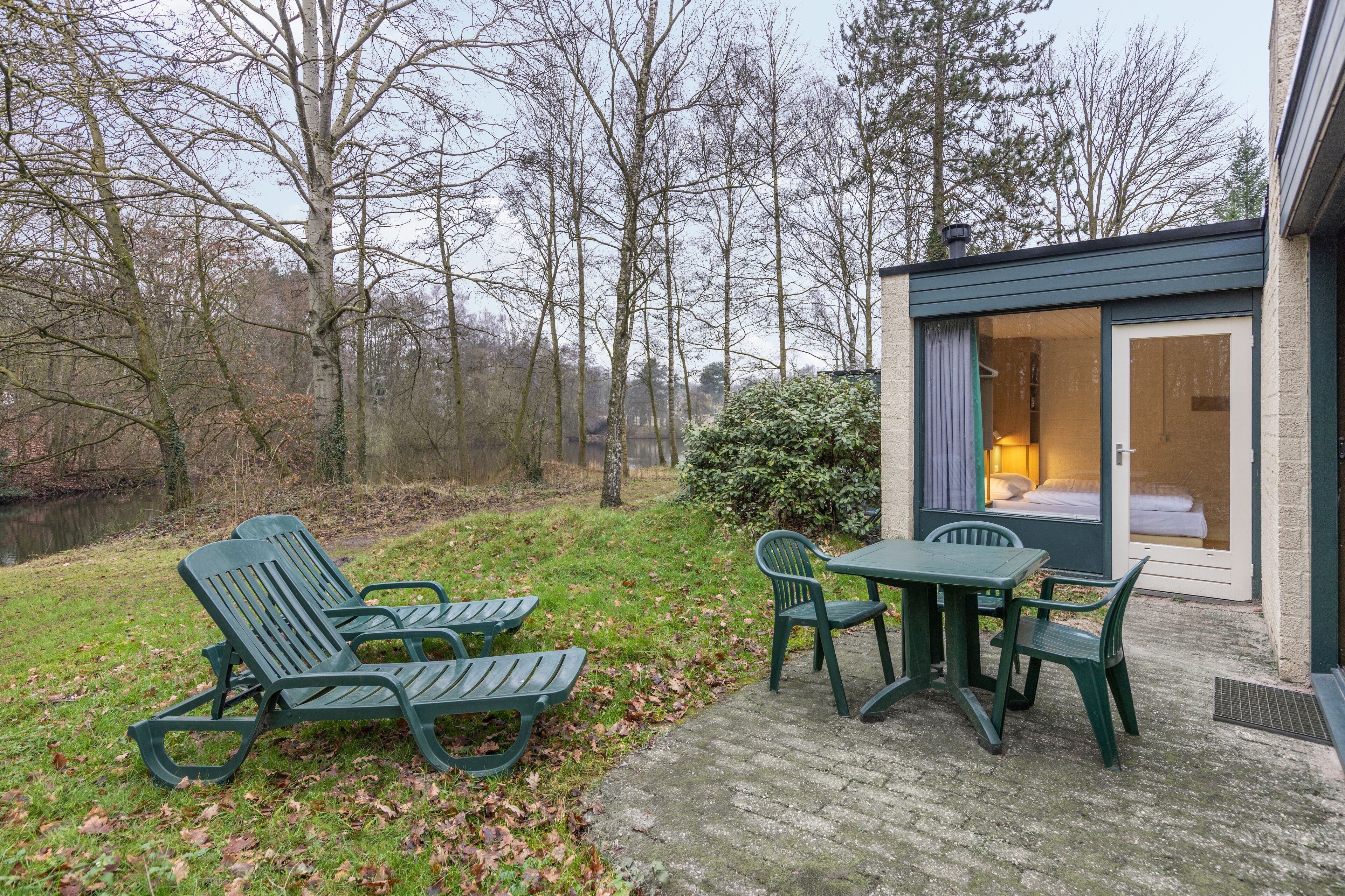 A cozy outdoor seating area with a table and chairs, a small garden, and a building with a sliding glass door.