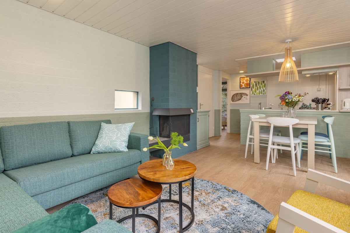Una sala de estar moderna con un sofá, una mesa de centro y una chimenea. Hay un comedor con una mesa y sillas.