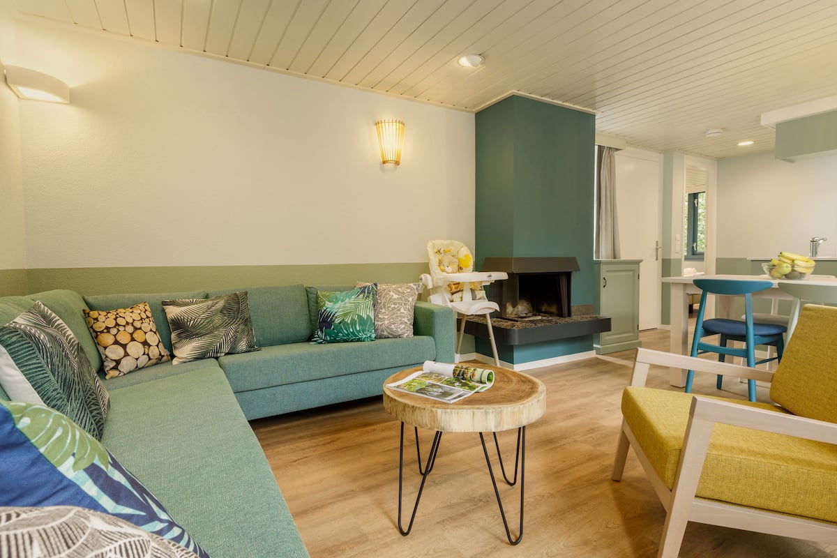Una sala de estar con un sofá, una mesa de centro redonda de madera y una zona de comedor con una mesa y sillas.
