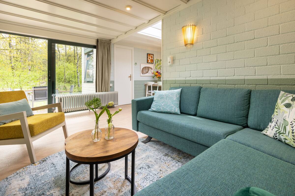 Una sala de estar moderna con un sofá verde, una mesa de centro de madera y un sillón amarillo.