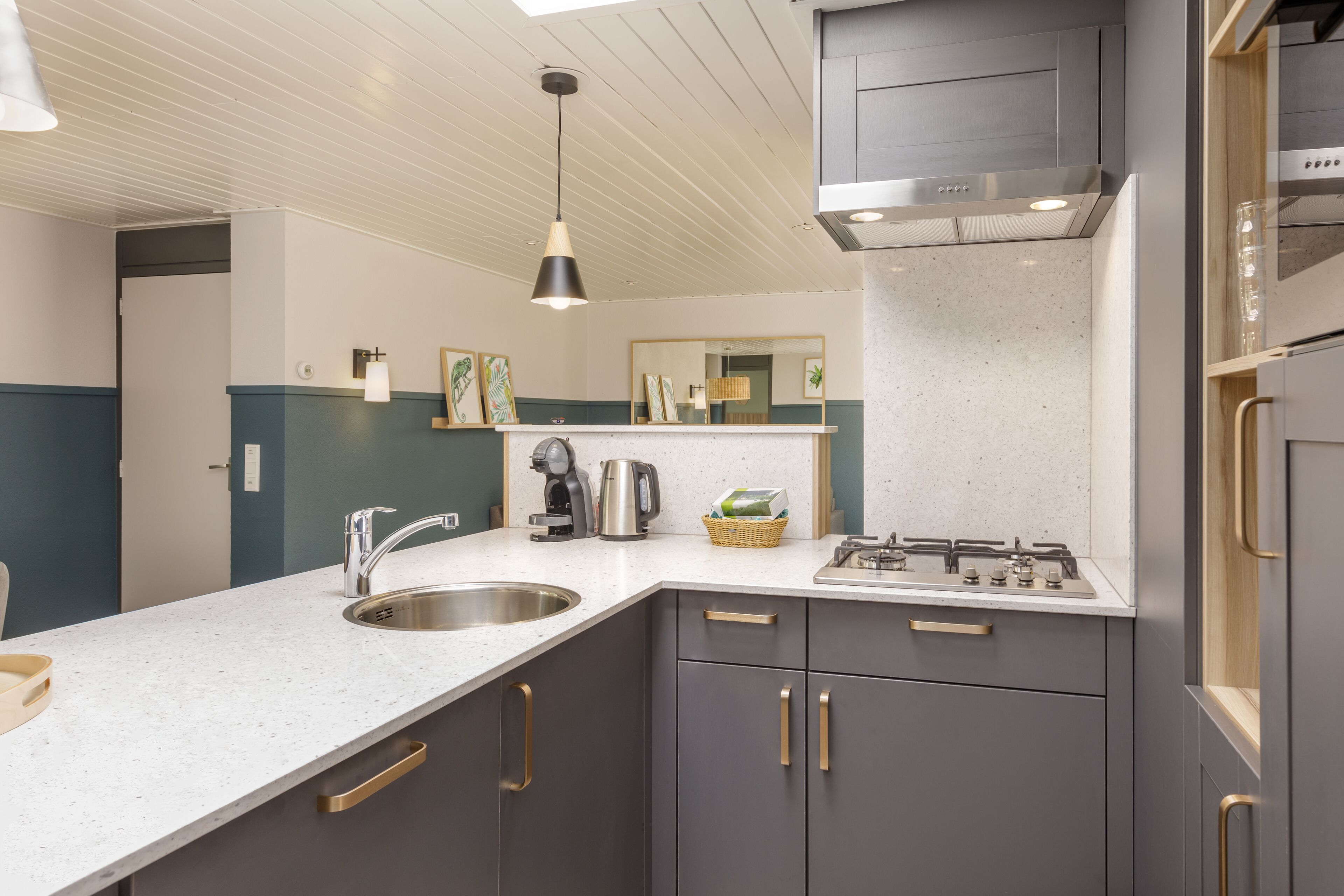 A modern kitchen with a white countertop, stainless steel sink, and dark cabinets.