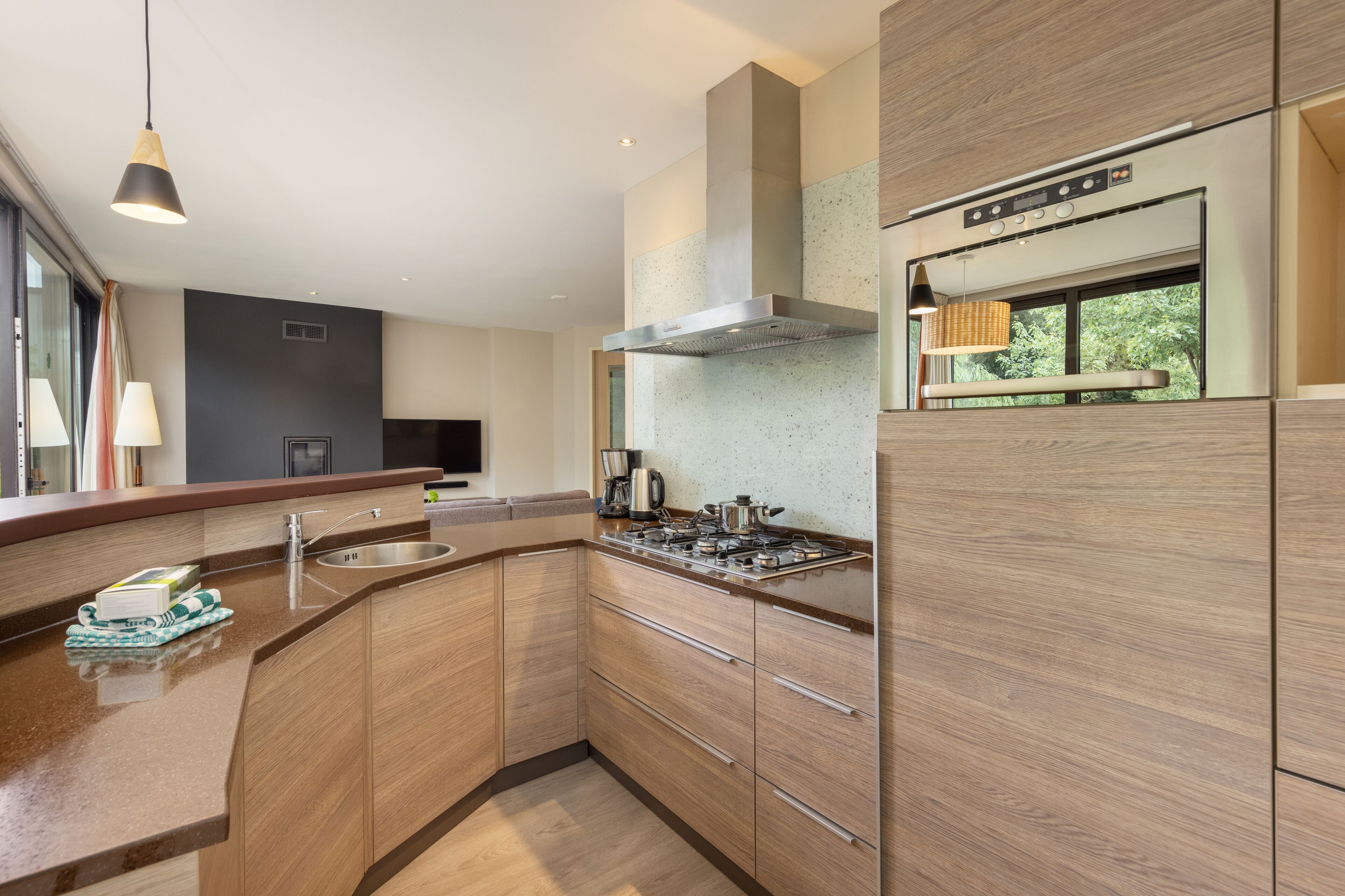 A modern kitchen with wooden cabinets, a stainless steel range hood, and a built-in oven.
