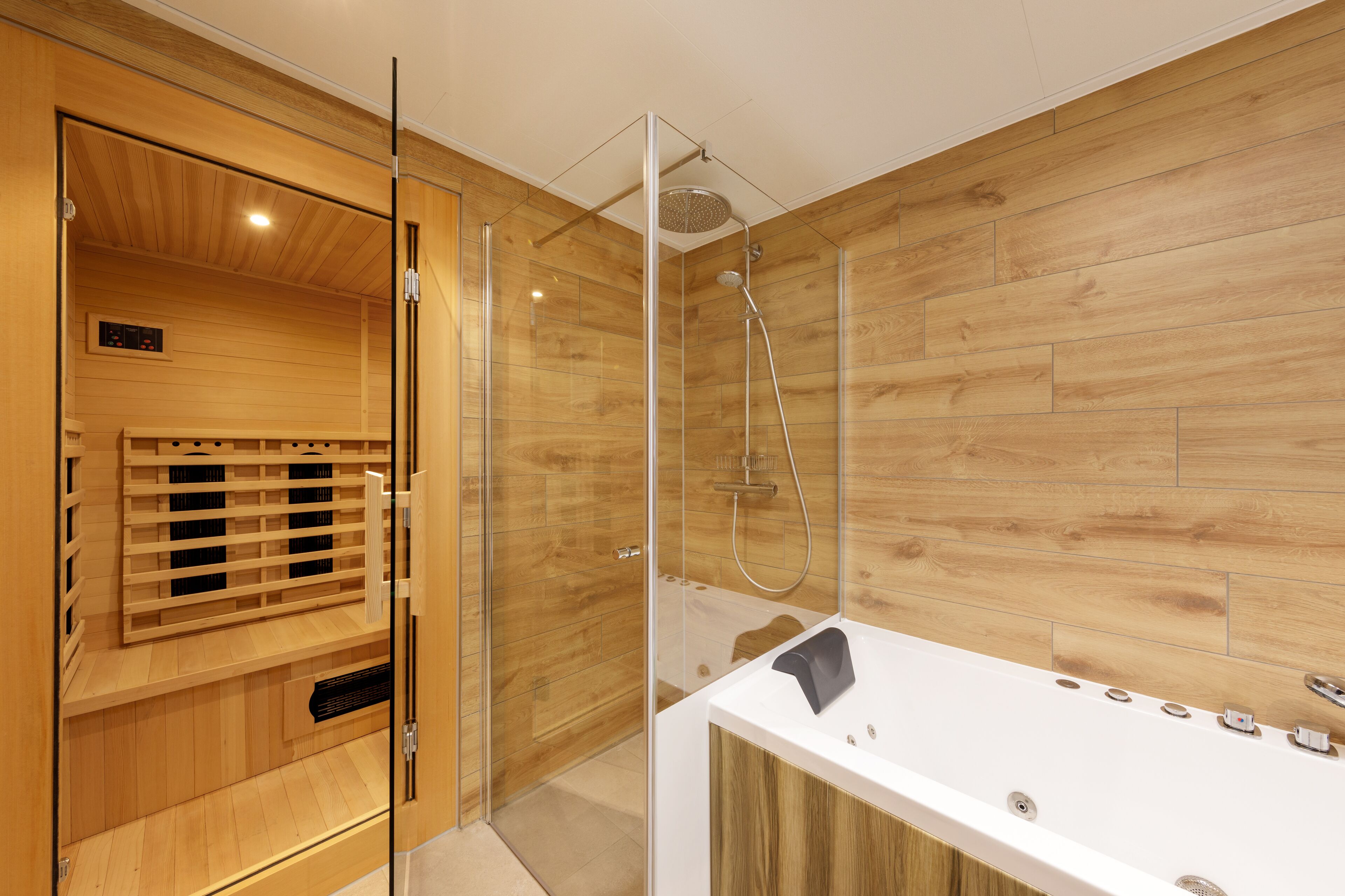 A modern bathroom with a wooden vanity, a glass shower enclosure, and a built-in sauna.