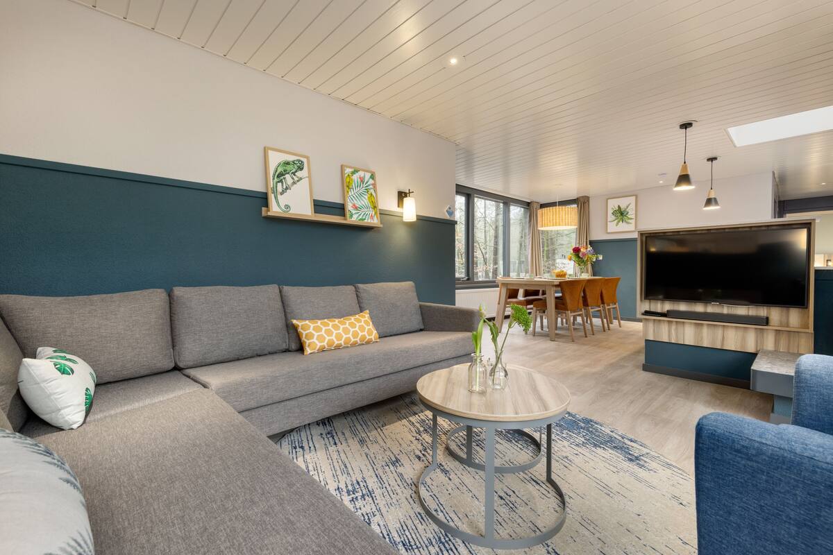 A modern living room with a grey sofa, a round coffee table, and a flat-screen TV.