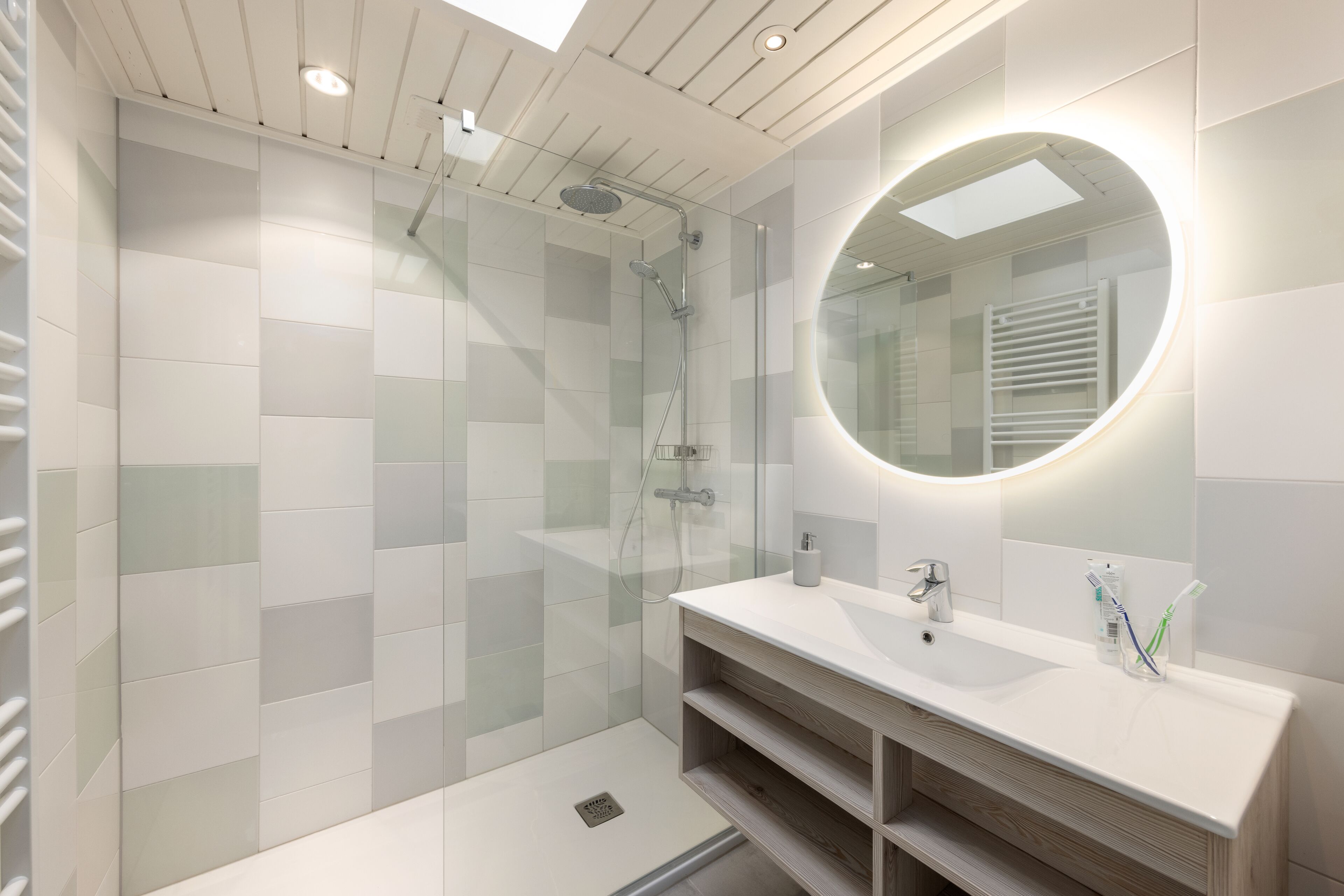 A modern bathroom with a glass-enclosed shower, a white vanity with a mirror, and a light fixture on the ceiling.