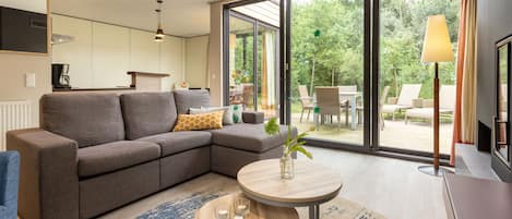 A modern living room with a sectional sofa, a small round table, and a view of the outdoors through large sliding glass doors.
