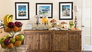 A breakfast buffet with fruits, juices, and pastries on a wooden counter.
