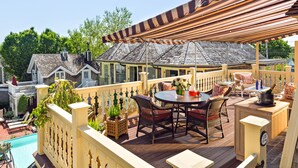 A covered outdoor patio with a pool, wicker furniture, and a bar area.