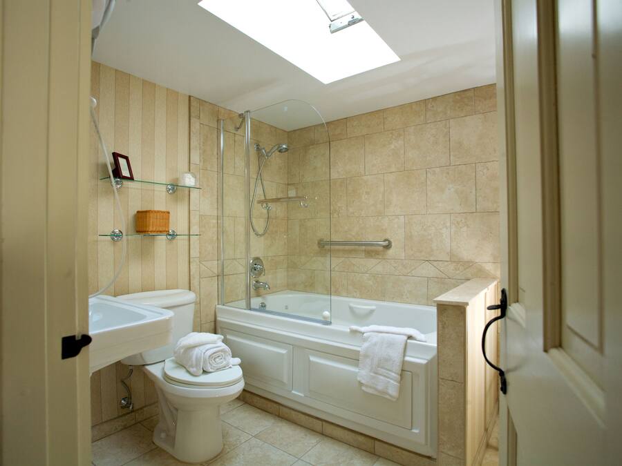 Un baño moderno con cabina de ducha de vidrio, bañera independiente y retrete.