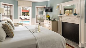 A bedroom with a bed, a fireplace, a television, and a view of the outside.