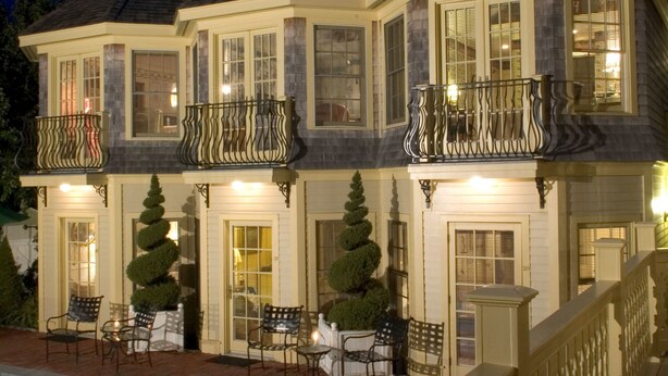 A large, multi-story house with a swimming pool, outdoor seating, and a balcony.