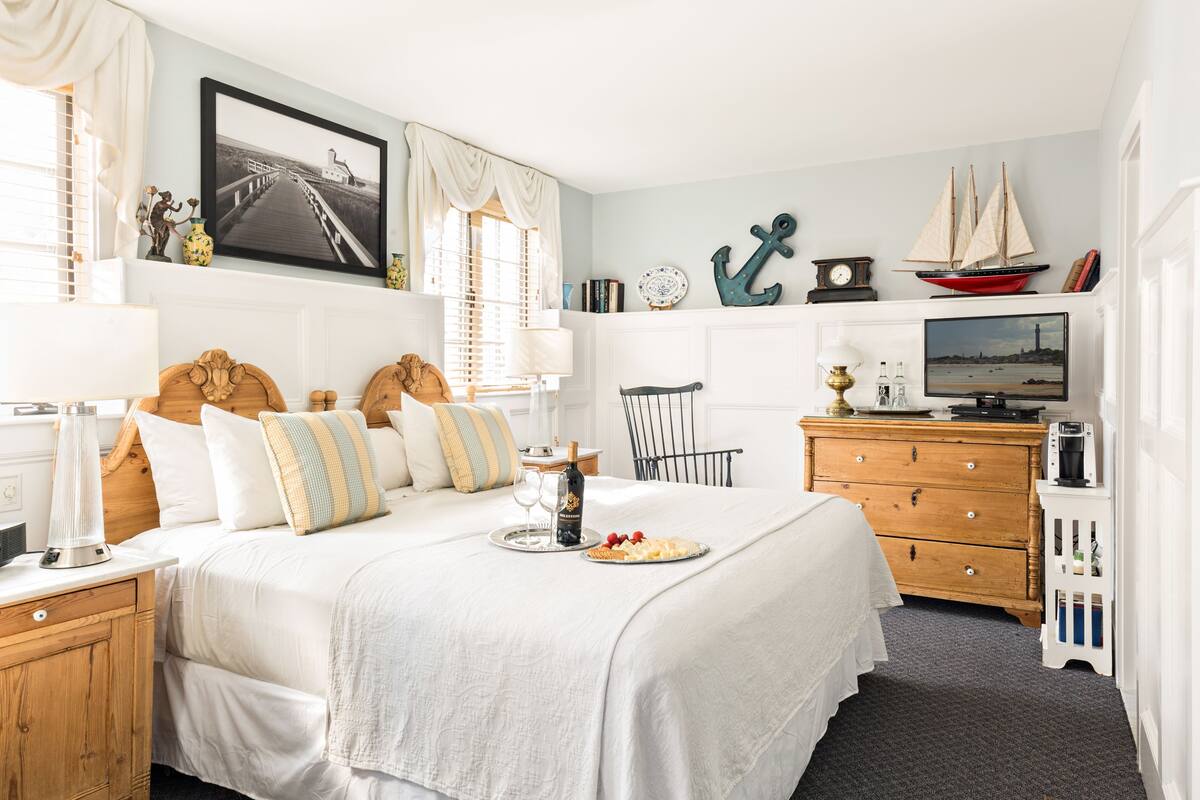 Une chambre à coucher bien rangée, avec un lit, des tables de chevet, une commode, un téléviseur et des objets décoratifs.
