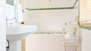 A bathroom with a white sink, a glass-enclosed shower, a bathtub, and a tiled floor.