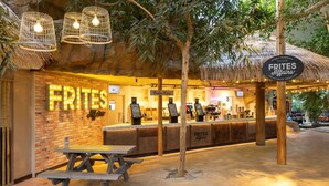 Un restaurante con pared de ladrillo, letrero de neón y zona de mesas al aire libre.