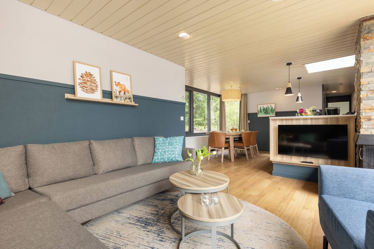 A modern living room with a sofa, a dining table, and a kitchen area with a TV.