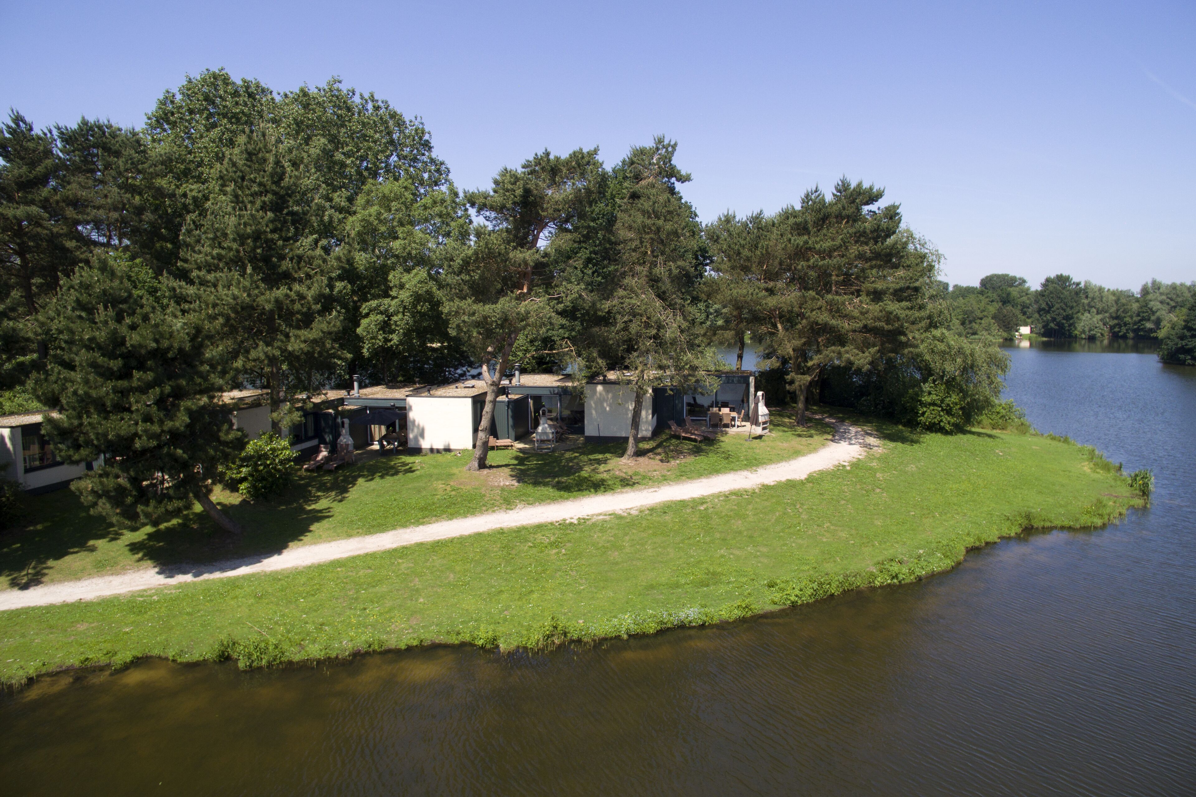 A lakeside campsite with RVs and tents, surrounded by trees and a clear sky.