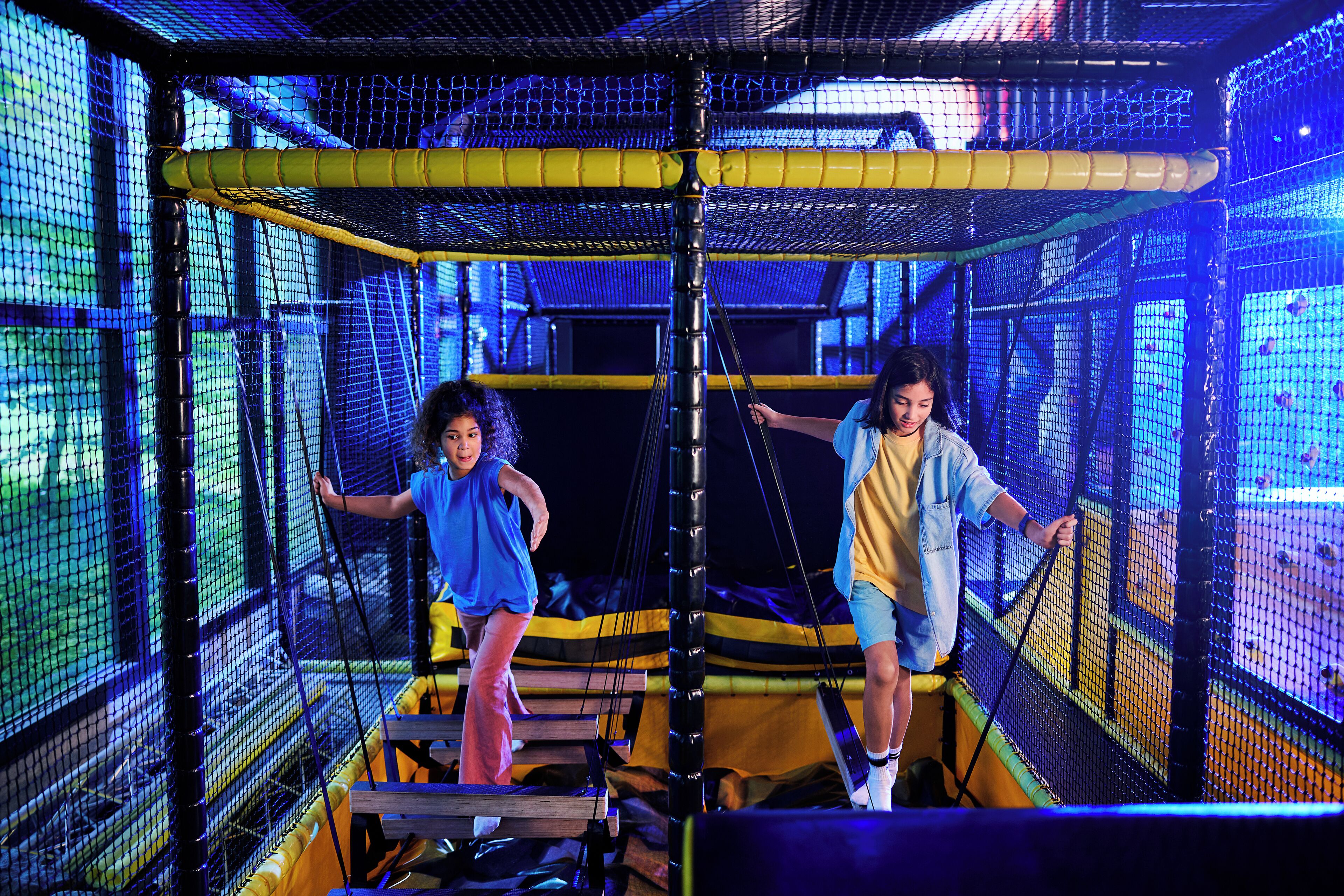 Un espace de jeux intérieur doté de structures en filet et de plateformes en bois.