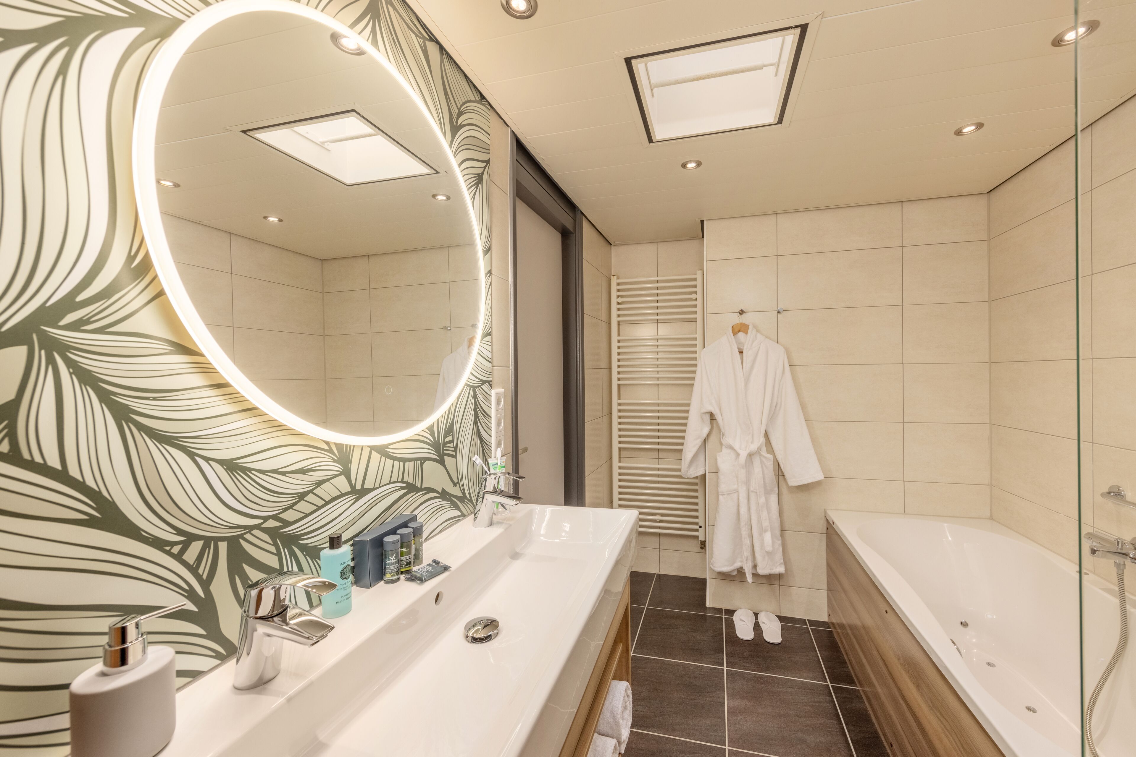 A modern bathroom with a large mirror, dual sinks, and a bathtub.